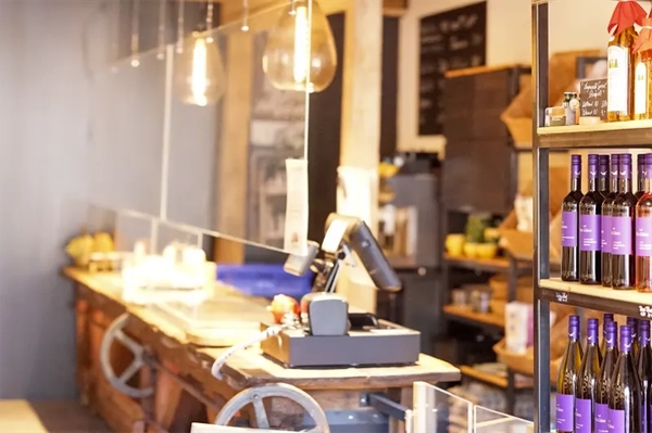 Moderner Kassenbereich im gemütlichen Campingladen vom Camping Langenwald mit warmen Licht, rustikalem Holztresen und Verkaufsregalen mit Regionaken Produkten