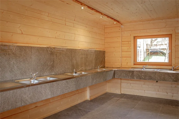 Moderner Warm beleuchteter Spülraum mit Holzwänden und Gefliesten Waschbecken im camping langenwald